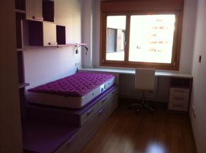 Habitación juvenil con cama en tatami, escritorio y estantería.