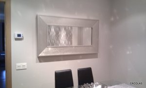 Espejo plata a juego con mueble de salón, sillas tapizadas en polipiel negra.